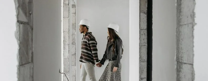 Deux personnes portant un casque de chantier dans un bâtiment en travaux