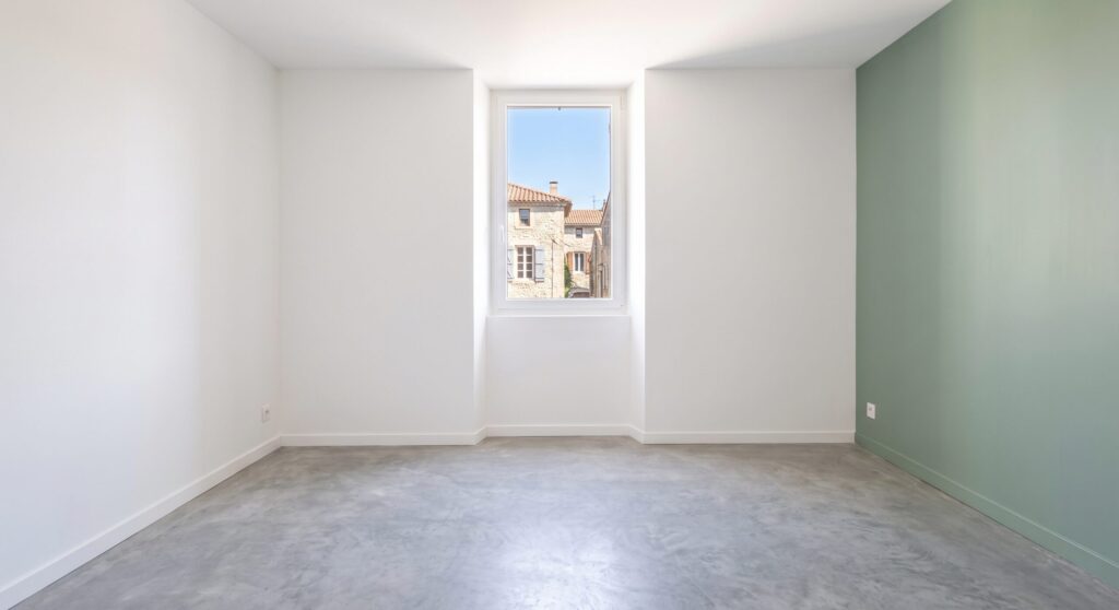 Pièce vide aux murs blancs et vert avec sol gris