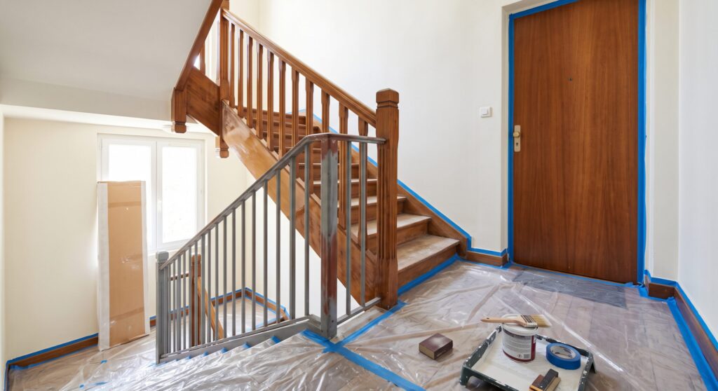 Palier avec escalier en bois, rambarde métallique, porte en bois et matériel de peinture