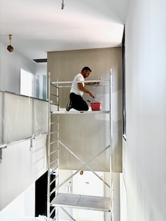 Artisan peintre sur échafaudage pendant une rénovation intérieure
