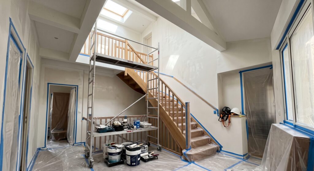 Escalier en bois sous une grande hauteur de plafond, avec échafaudage et protections