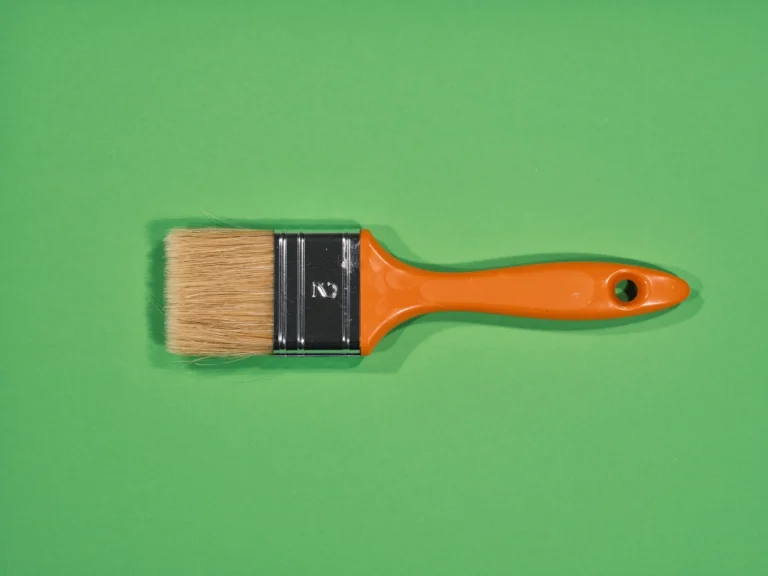 Pinceau à manche orange posé sur un fond vert