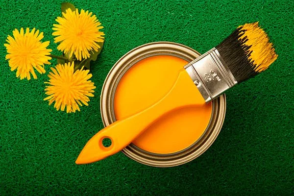 Pot de peinture jaune et pinceau entourés de fleurs sur un fond vert