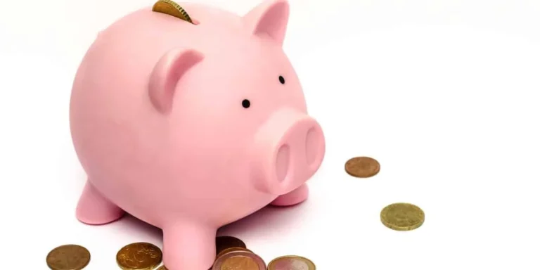 Tirelire rose en forme de cochon entourée de pièces de monnaie